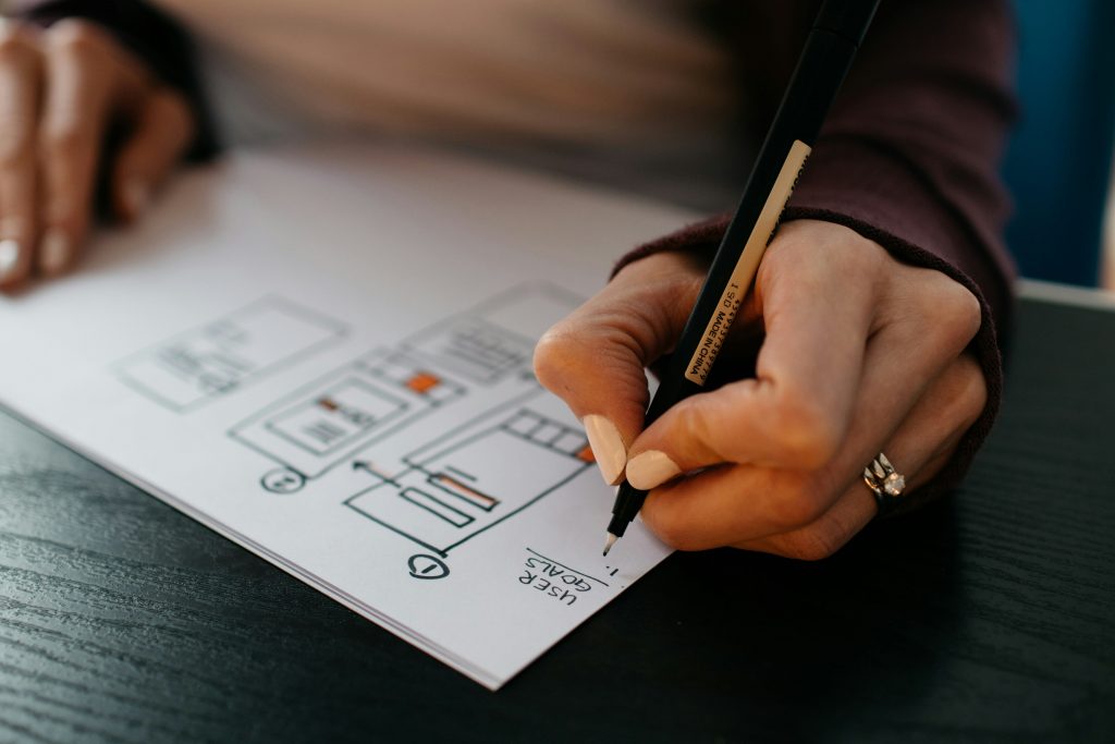 Hand zeichnet mit Stift ein Website-Layout auf Papier – Symbol für professionelles Webdesign und kreative Planung.